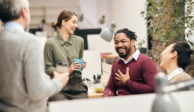 Multi-ethnic group of entrepreneurs laughing while talking to each other on a break in the office.