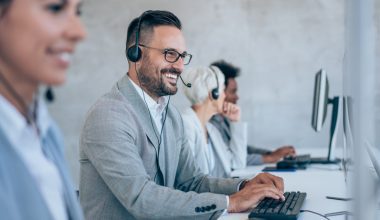 A cheerful man in a call center, equipped with headphones, providing assistance to a client over the phone.