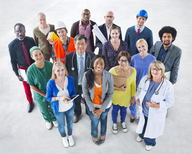 A diverse group of people in professional attire representing occupations like healthcare, construction, engineering, and business, standing in rows and looking up at the camera.