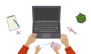 Top-down view of a workspace with a laptop, baby items, and adult and child hands reaching for a bottle.