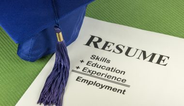 A graduation cap resting on a resume that highlights skills, education, and experience.